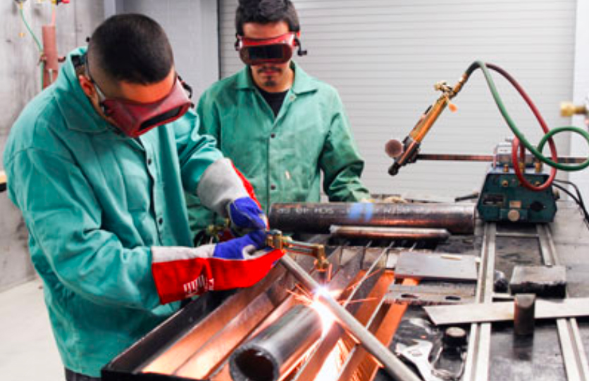 Two students practice welding in welding lab