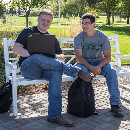 Two students sit outside on campus 