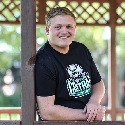 Student resting against gazebo on campus.