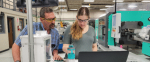 Student and teacher are looking at computer for injection molding.