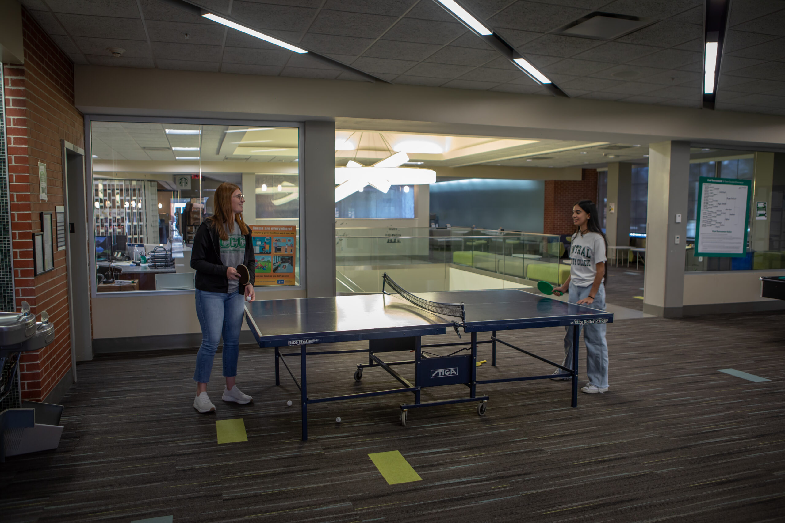 Two students playing ping pong in student union.