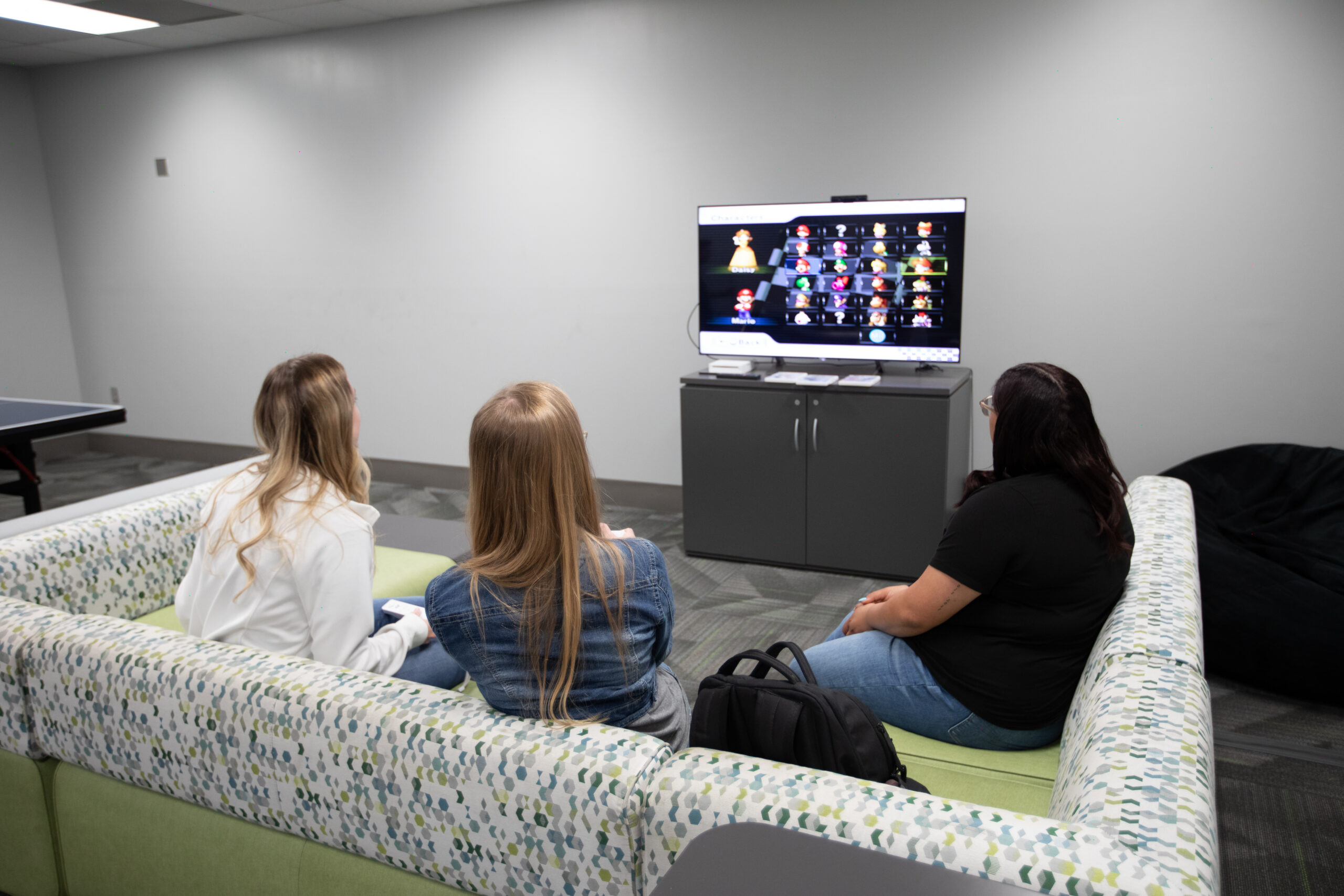 Three students watching TV while sitting on couch.
