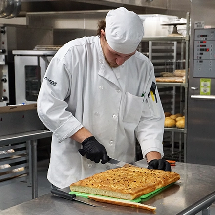Culinary student slicing a large pastry