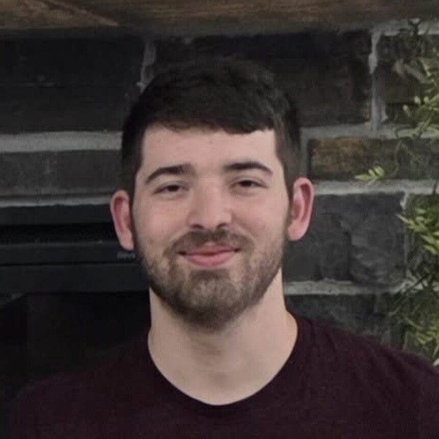 Cooper Casey smiling at the camera with brick wall behind him