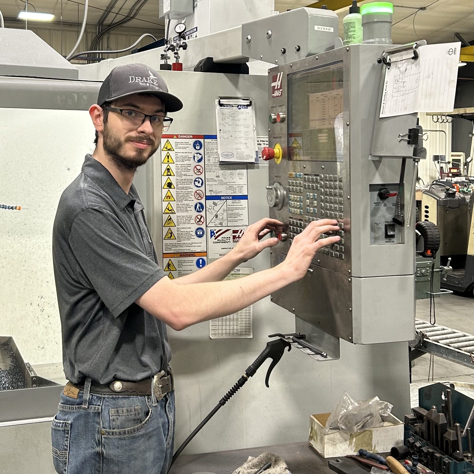 Man operating CNC machine in drafting and design lab