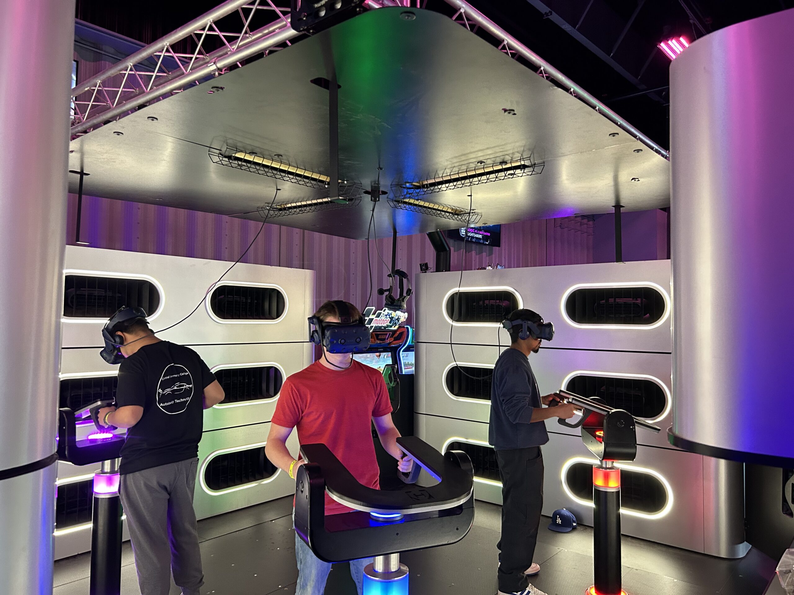 People wearing VR headsets use illuminated motion platforms in a futuristic VR gaming room.