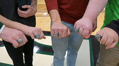 Five esports team members show their rings for winning national titles.