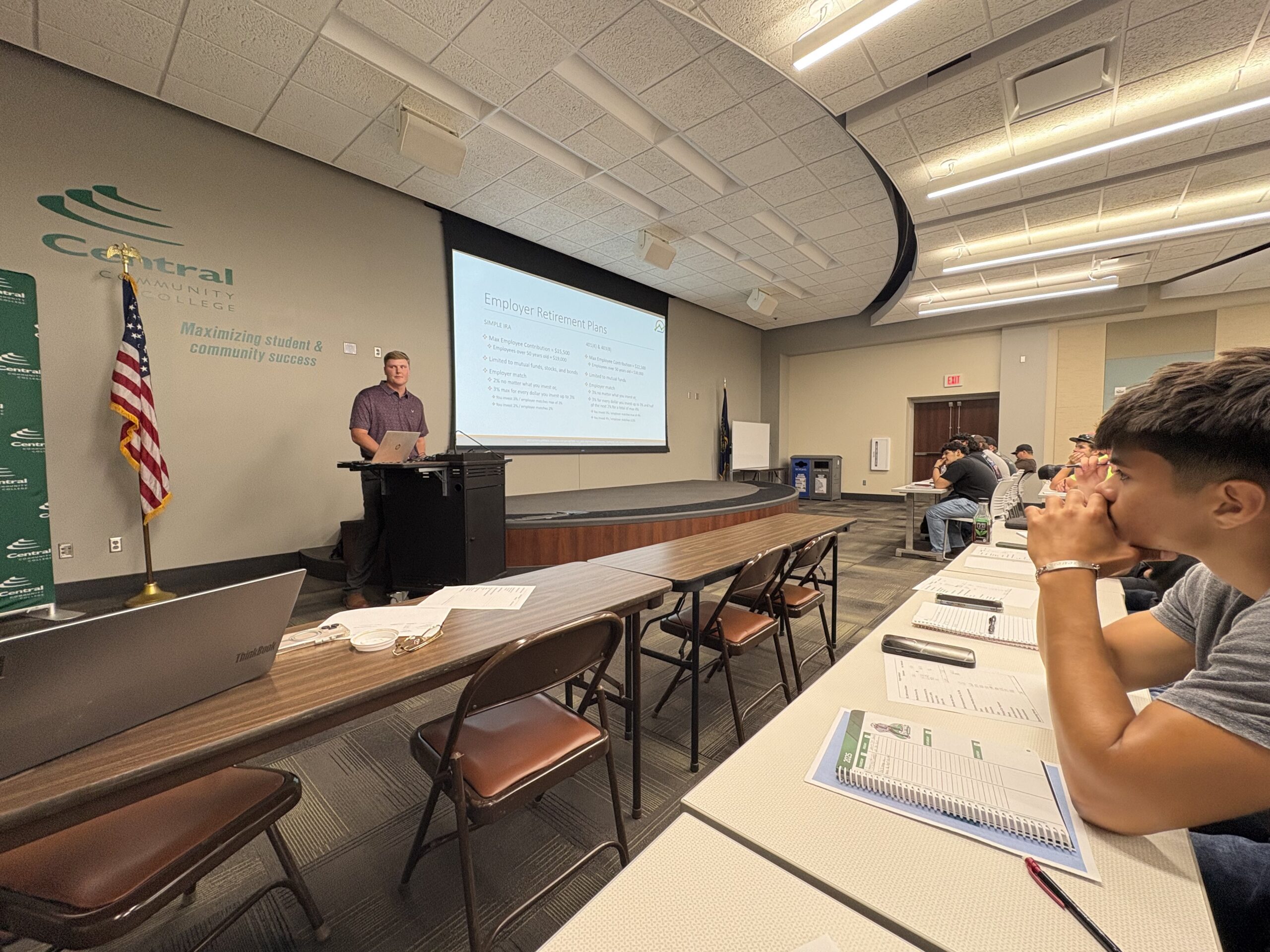 Instructor presents financial literacy workshop to seated students in a lecture room.
