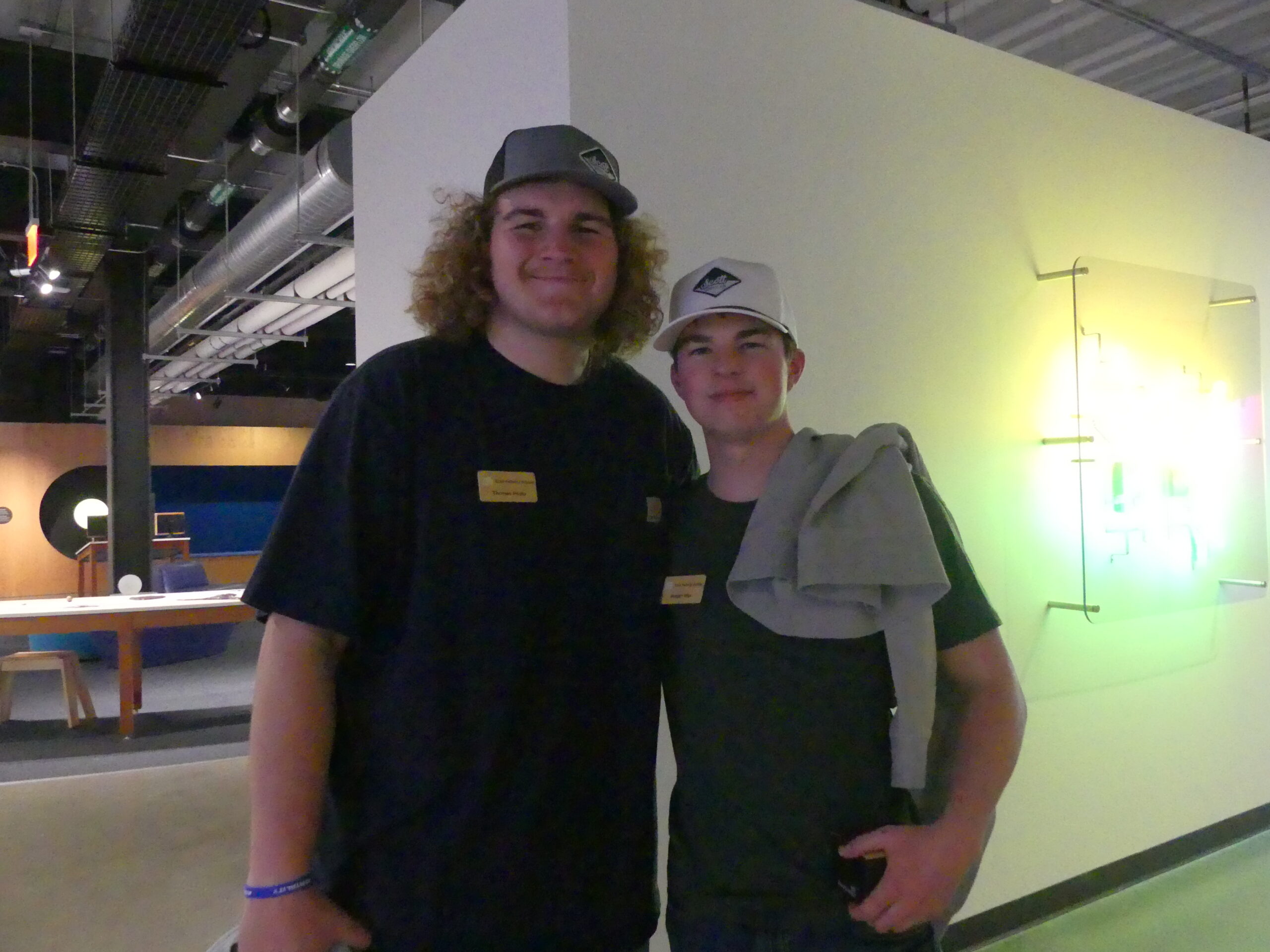 Two people stand side by side wearing name badges inside an exhibit hall.