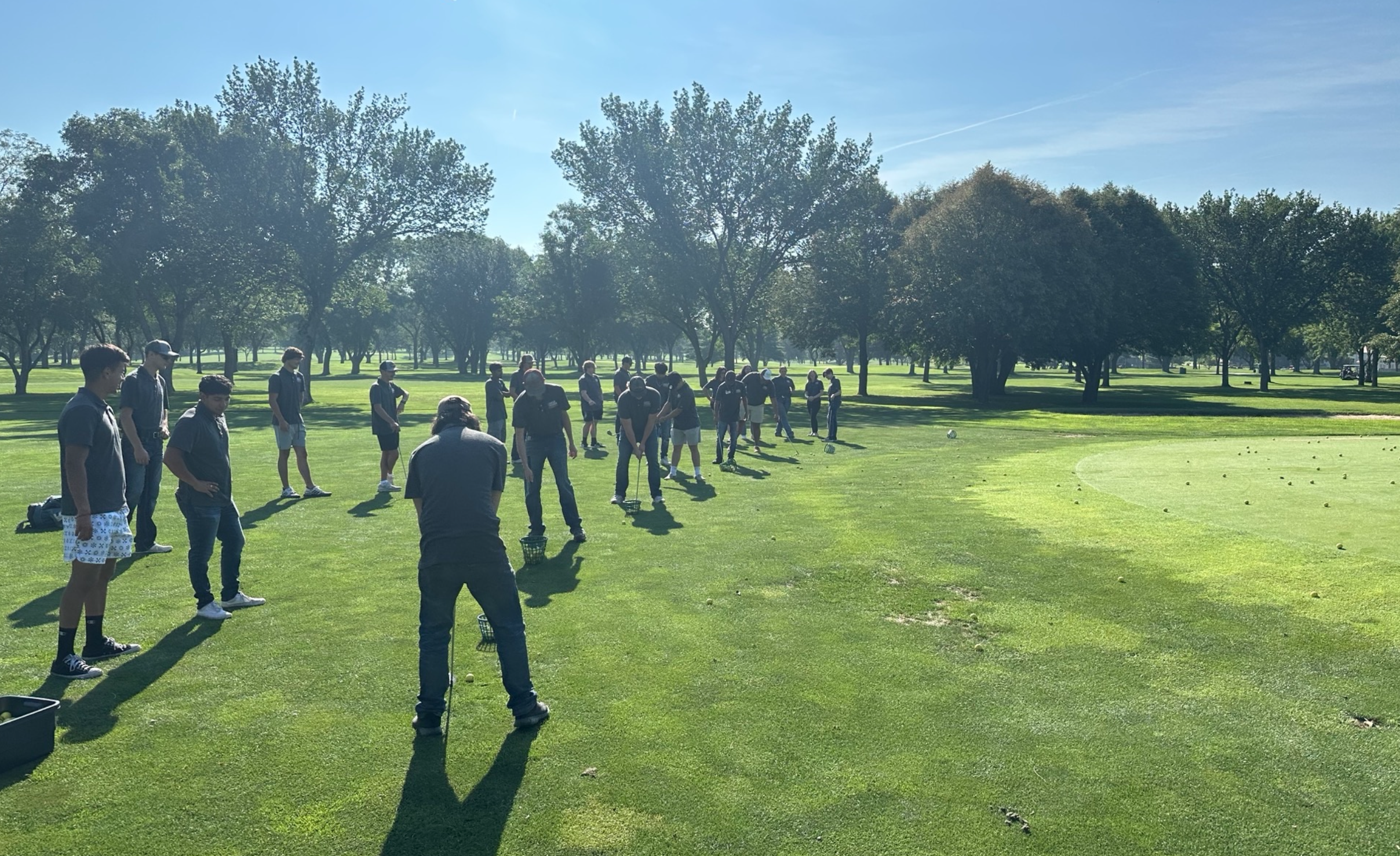 Group stands on a golf course during a putting or golf skills activity.