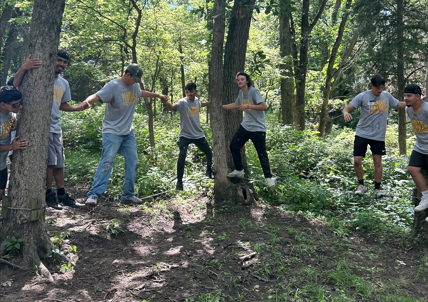 Group balances on ropes between trees during an outdoor challenge course.
