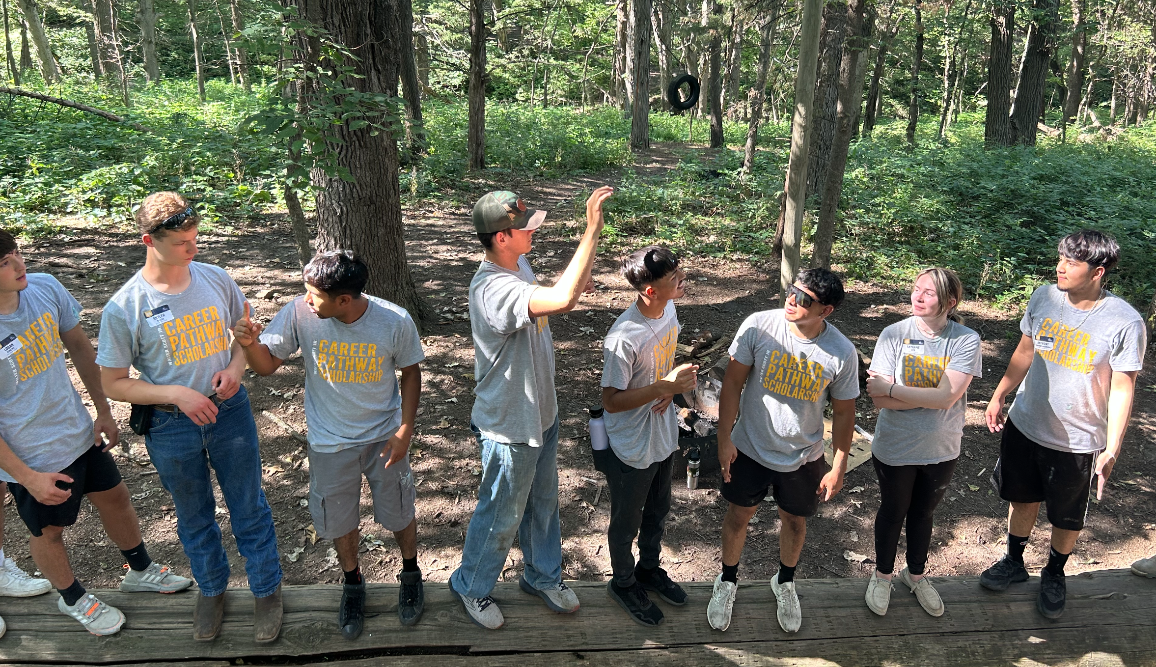 Participants stand on a wooden platform during a forest team-building activity.