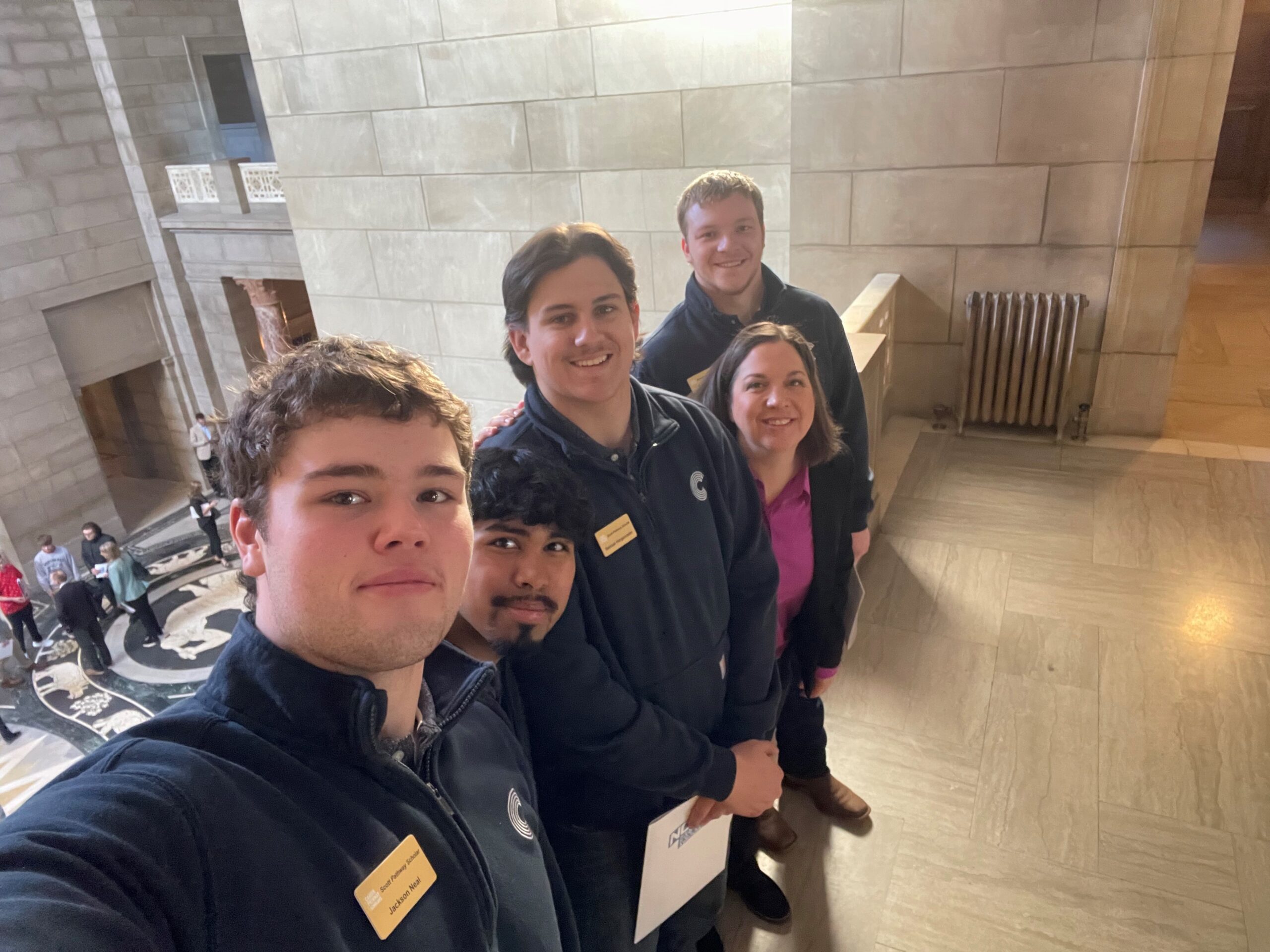 Five people take a selfie inside a large stone building with open interior space.
