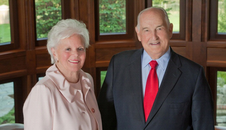 Suzanne and Walter Scott, Jr. standing in front of a row of windows
