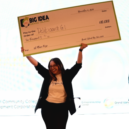 Previous Big Idea winner holding check above head in celebration